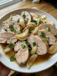Slices of juicy slow cooker turkey breast arranged on a white serving platter with parsley.