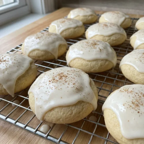 A stack of round eggnog cookies with white icing on a festive platter.