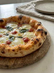 A finished pizza on a wooden peel, with a bubbly cheese topping and a golden-brown crust.
