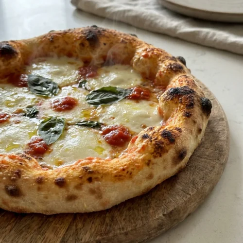 A finished pizza on a wooden peel, with a bubbly cheese topping and a golden-brown crust.