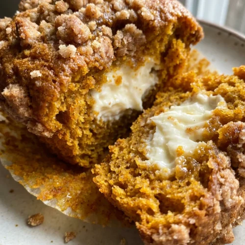 A dozen pumpkin cream cheese muffins arranged on a rustic wooden board.